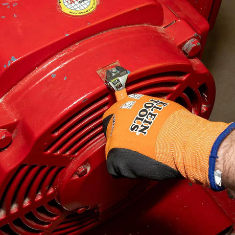 Person using Klein Tools O5064 Extra Capacity Jaw 4 Inch Adjustable Wrench for tight spaces on red equipment with glove
