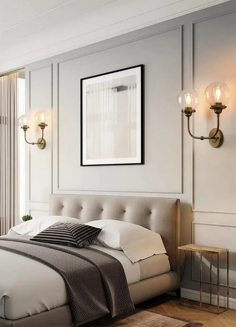 Antique Brass Double Sconce Wall Light With Clear 5.9 Inch Globe Shade in a bedroom setting, E26 Base, 110-120V, 60W Max