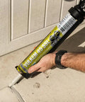 Person applying Pro Grade Polyurethane Sealant For Concrete Brick And Stone Heavy Duty Horizontal Formula on a cracked sidewalk with a caulking gun.