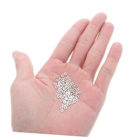 Hand holding 200 metal flat washers for eyeglasses replacement gaskets rimless glasses quick repair kit for sunglasses and eyeglass frames.