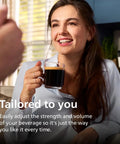 Fully Automatic Espresso Machine Crushing Your Morning Cravings With One Touch Brewing And Classic Milk Frother For Silky Cappuccinos Featuring Precision Ceramic Grinder And Sleek Black Touch Display - woman enjoying brewed coffee in kitchen.