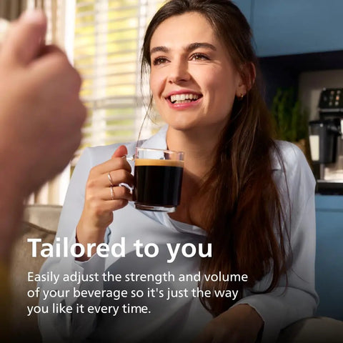 Fully Automatic Espresso Machine Crushing Your Morning Cravings With One Touch Brewing And Classic Milk Frother For Silky Cappuccinos Featuring Precision Ceramic Grinder And Sleek Black Touch Display - woman enjoying brewed coffee in kitchen.