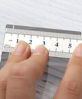Close-up of 15 Cm Straight Ruler For Drafting And Math Class Double Sided Metal Tool with precise measurements in hand
