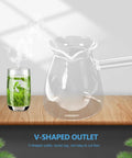 Clear glass teapot with a V-shaped outlet beside a glass of green tea on a wooden surface.