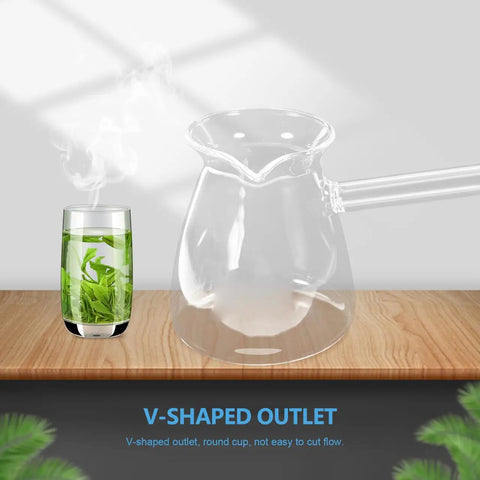 Clear glass teapot with a V-shaped outlet beside a glass of green tea on a wooden surface.
