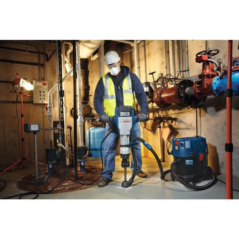Worker using Bosch HDC400 1-1/8 In Hex Chiseling Dust Collection Attachment with rotary hammer in industrial setting