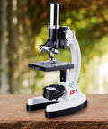 Rock Solid 1200X Monocular Compound Microscope With Killer LED Lighting And A Straight Up 52 Piece Science Starter Kit For Students Crushing Biology And Chemistry Labs on a wooden table.
