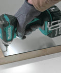 XT269M 18V LXT Brushless Cordless Impact Driver drilling into a metal surface, operated by person wearing glove, close-up view
