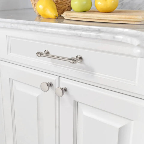 Close-up of kitchen cabinet with stainless steel handles and a marble countertop, featuring lemons and limes on a wooden board.