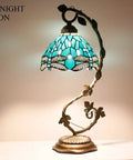 Green Stained Glass Dragonfly Tiffany Style Table Lamp With Metal Leaf Accent, cozy desk reading light in night mode.
