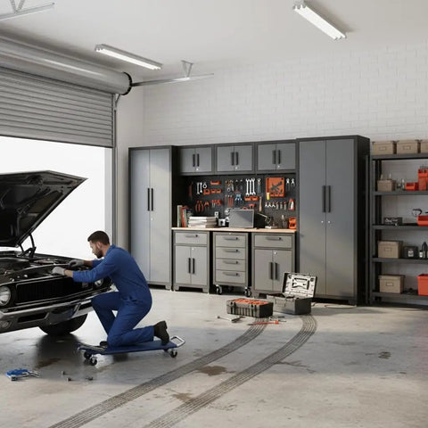 Mechanic working near 9-Piece Garage Storage Cabinet System with Corner Cabinet, Workbench, Pegboard and Roller Drawers for Tool Organization in Black and Gray.