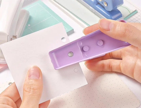 Hands using Rugged Heavy Duty Single Hole Punch for Papers and Crafts 40 Sheets Capacity One Quarter Inch Purple Hole Puncher