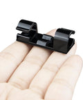 Hand holding a black clip from 50 Piece Self Adhesive Cable Management Clips Set For TV PC Laptop And Ethernet Cables No Mess Sticky Wire Clips Cord Holder Easy Tidy Organization For Desktop Home Office.