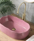 UMJIGF Vessel Sink Household Washbasin Bathroom Above Counter Basin in pink, installed with a golden faucet and wooden countertop.