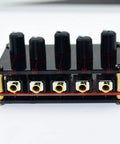 Front view of Four Channel One Eighth Inch Stereo Passive Mixer with black acrylic shell, gold ports, and volume knobs, 3.29x2.13x0.83in.