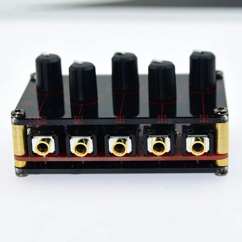 Front view of Four Channel One Eighth Inch Stereo Passive Mixer with black acrylic shell, gold ports, and volume knobs, 3.29x2.13x0.83in.