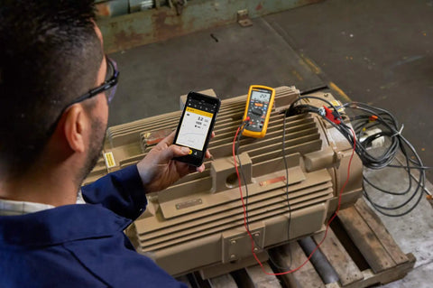 Technician using 1587 FC 2 In 1 Insulation Multimeter With Fluke Connect Measurements App on industrial equipment
