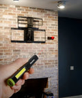 Hand holding Rechargeable Inspection Pen Light With 450 Lumen Flood And 140 Lumen Spot, 365 Nm UV Light near wall