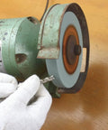 Using Heavy Duty Seven Inch Bench Grinding Wheel 100 Grit Chrome Corundum to sharpen metal drill bit on grinder.