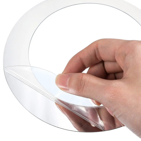 Close-up of a hand peeling adhesive backing from Dope 32 Piece Adjustable Acrylic Mirror Wall Decals Set Removable Round Mirror Stickers