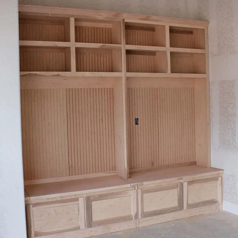 Wooden built-in shelving unit with beadboard backing and storage compartments in unfinished room