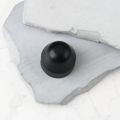 Black rubber 4Pcs Dope E Bike Wheel Nut Cap 21mm inner diameter on white stone surface.