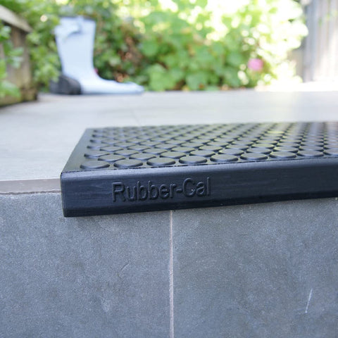 Close-up of Coin Grip Grippy Non Slip Rubber Tread Stair Mats 6 Pack Black on outdoor steps, featuring coin pattern and Rubber-Cal branding.