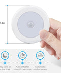 Hand holding a 3.15 inch Upgraded Motion Sensor LED Light Stick On Battery Powered Night Light with auto-on feature in white.