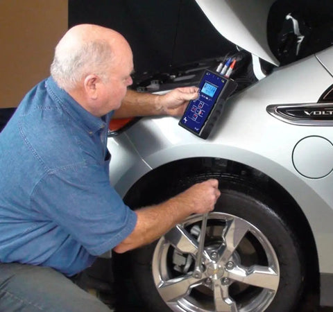 Technician using EV Motor Tester Deenergized Circuit Analysis Diagnostics on a silver hybrid car tire.