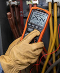 Hand holding ET600 Multimeter Megohmmeter Insulation Tester with Auto-Ranging TRMS Readouts in electrical panel