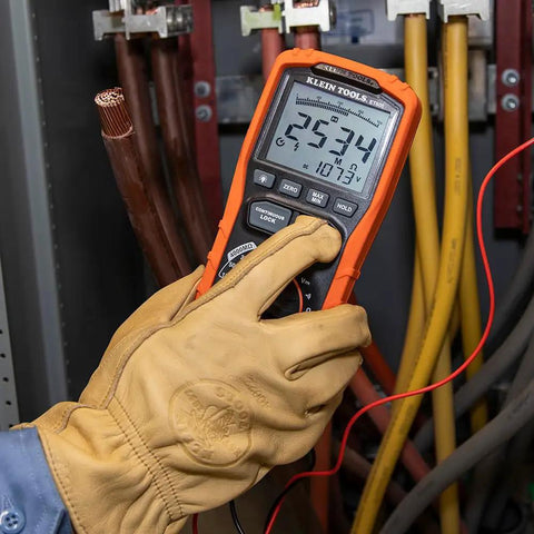 Hand holding ET600 Multimeter Megohmmeter Insulation Tester with Auto-Ranging TRMS Readouts in electrical panel