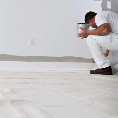 Painter using Heavy Duty 12 Ounce Canvas Drop Cloth 9 By 12 Feet for paint protection on floor indoors, handling spills with ease.