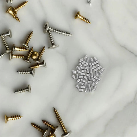 Solid Stainless Steel Cylindrical Dowel Pins Bulk Pack For Woodwork, Furniture Assembly And Industrial Builds High Strength Corrosion Proof Metal Fastener Hardware Pegs among various screws on marble background.