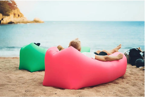 Person lounging on beach with Inflatable Lounger Air Sofa Hammock For Outdoors Camping Beach And Festivals Portable Waterproof Couch Quick To Fill By Wind Or Fan Anti Leak Pouch Design Easy Inflate Black.