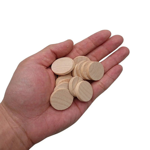 Hand holding multiple 1 inch smooth edge unfinished round wood slices from 60 Pack 1 Inch Natural Wood Slices Unfinished Round Wood Cookies Real Deal Smooth Edged Pro Gear DIY Crafting Supplies Mini Wooden Disks For Paint Room Decor Makeovers.