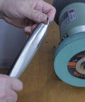 Hand holding a polished stainless steel piece next to a bench grinder, showcasing Six Inch Elastic Polyurethane Buffing Wheel Two Thousand Grit Yields Ridiculously Smooth Mirror Polish On Stainless Steel And Copper With Three Quarter Inch Arbor Knockout Addition To Your Bench Grinder Setup.