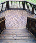 Top Shelf Heavy Duty Oil Based Wood Stain For Exterior Decks Fences Siding Logs Featuring Knockout UV Shielding And Deep Soak Water Repellent Formula In Easy Roll Semi Transparent Rustic Brown Covers Large Patios on a wooden deck with railings.