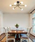 Kickass Modern Sputnik Chandelier Ceiling Light Fixture With Six Bulbs For Dining Rooms above a wooden dining table in a bright space.