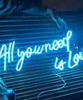 All You Need Is Love Neon Sign LED Light For Home Bar Party Decor, Customizable Neon Wall Art, 60x26cm displayed on a bench