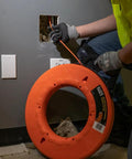 Professional Grade 200 Foot Non Conductive Fiberglass Fish Tape Featuring Multi Groove Low Friction Design And 500 Pound Pull Rating For Zero Stress Wiring Hustle in use through wall conduit.