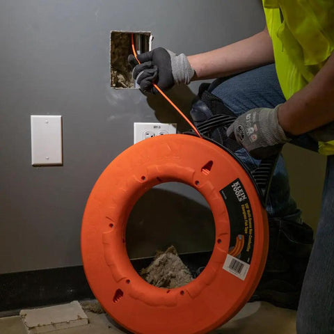 Professional Grade 200 Foot Non Conductive Fiberglass Fish Tape Featuring Multi Groove Low Friction Design And 500 Pound Pull Rating For Zero Stress Wiring Hustle in use through wall conduit.