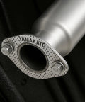 Close-up of YAMAKATO 62mm 2-bolt high-temp exhaust gasket flange with perforated metal; two bolts visible.