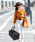 Woman carrying Beefy 56L 24Inch Sports Duffel Bag Set With Upgraded Zipper Water Resistant Foldable Gear Tote, city street.