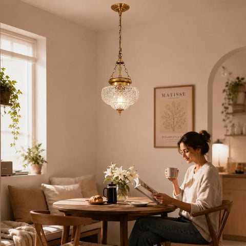 Straight Up Vintage Vibes Handblown Textured Glass Pendant Light With Brushed Antique Brass Finish illuminating a dining table.