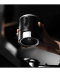 Espresso Gang Verified Shaker Funnel With Built In Dosing Cup For 58mm Portafilter shown in hand, highlighting stainless steel and black finish.