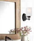 Phoebe 8 Inch Modern Wall Sconce With Frosted Seeded Glass Cylinder Shade in bathroom, oil rubbed bronze finish near mirror