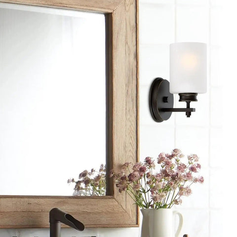Phoebe 8 Inch Modern Wall Sconce With Frosted Seeded Glass Cylinder Shade in bathroom, oil rubbed bronze finish near mirror