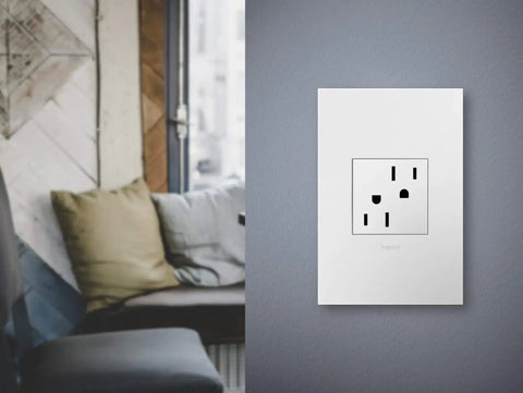 Adorne 15 Amp Tamper-Resistant Outlet With Matching Wall Plate, Gloss White, installed on grey wall, living room view, UL Listed