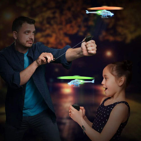 Adult and child launching Light Up Flying Helicopters Set Of 2 With LED Lights And Handheld Launcher in night setting