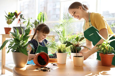 Child and adult gardening indoors with plants from Kids Metal Garden Tool Set For Little Green Thumbs With Real Shovel Rake Fork Trowel Sun Hat Apron Gloves Tote Bag Sprayer and Bucket Educational Outdoor Garden Gift